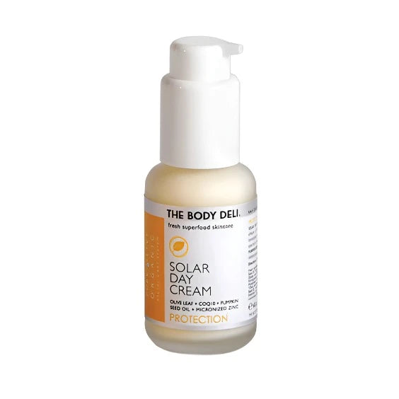 A pump bottle of 'The Body Deli' Solar Day Cream with a white label and orange accents, indicating SPF protection.