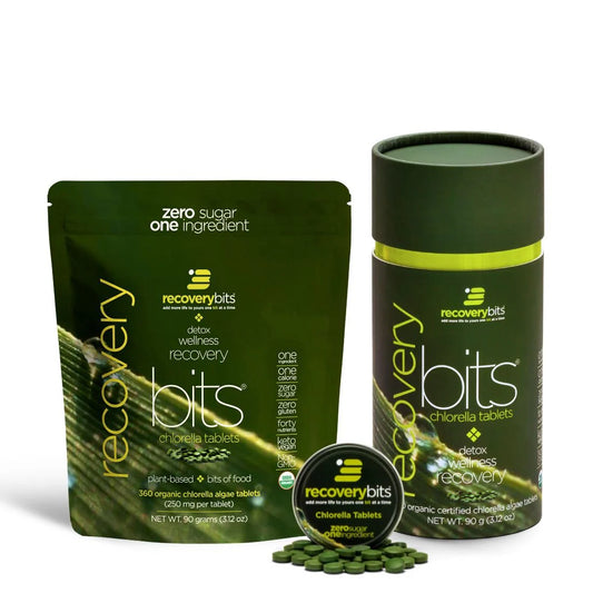 The image shows a small canister of RECOVERYbits chlorella algae tablets alongside its packaging. The package is predominantly green with text detailing the product's benefits and organic certification.